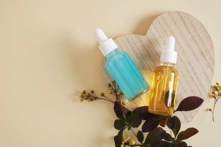 bottles with pipettes for cosmetics for serum or oil mok-up on a wooden stand in the shape of a...