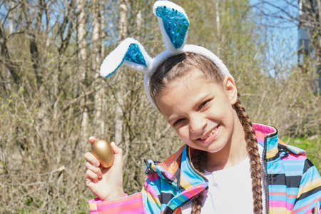 portrait of smiling young girl wearing traditional bunny ears headband for Easter. spring time,...