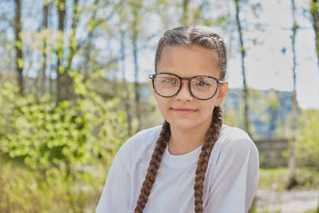 portrait of cute teenage girl in eye glasses in park