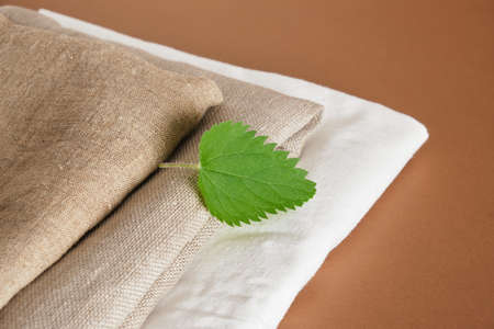 fresh nettle leaf and natural fabrics on a brown background, natural nettle fabrics, fashionable eco-friendly materials, modern and traditional technologiesの写真素材
