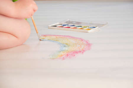 kid painting rainbow, little girl painting colorful rainbow on large sheet of paper, watercolorsの写真素材
