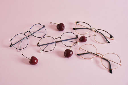 cherries and Fashion Trendy Eye Glasses, several pairs of eye glasses frames pink background copy...