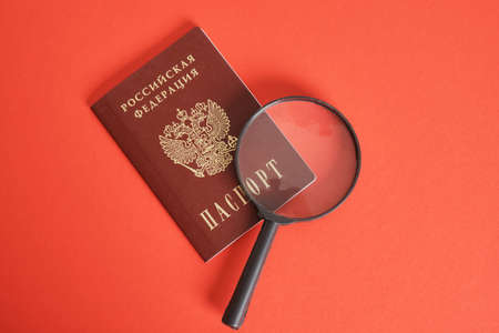 Russian passport and a magnifying glass on a red background, finding solutions to the problem, getting out of the crisisの写真素材