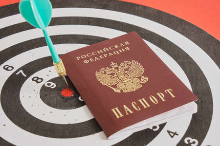 passport of a citizen of the russian federation and a dart on a darts board, politics concept, travel and crisisの写真素材