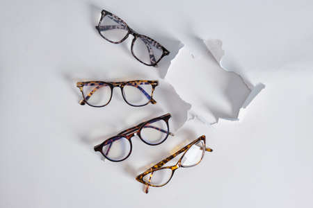 several fashion eye glasses in light gray paper with torn hole, creative background leopard print...