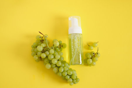 mock up blank bottle with green gel and grapes on yellow backgroundの写真素材