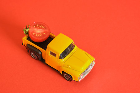 yellow retro pickup truck and small cherry tomatoes on red background, harvesting, ketchup...
