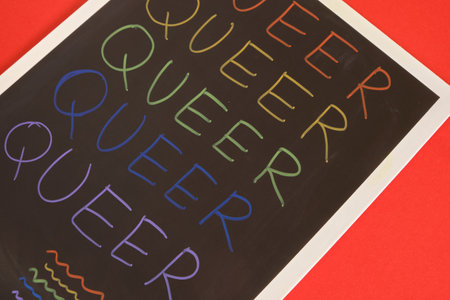 coloful inscription queer on black board on red background words written in rainbow colors ride conceptの写真素材