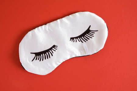 sleeping mask with painted eyelashes on red background copy space top viewの写真素材