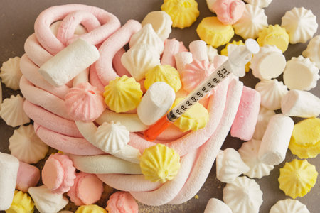 insulin syringe, meringue and marshmallows on a red background, diabetes concept, the harm of sweets for blood and heart, high blood glucose, hypoglycemiaの写真素材