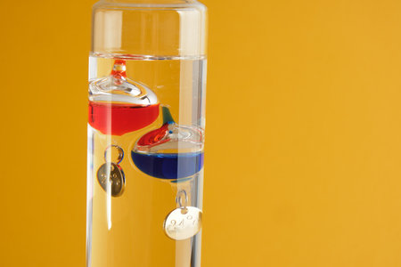 Alcohol thermometer for measuring air temperature close up yellow backgrund