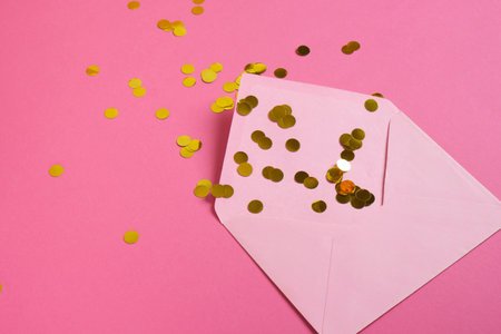 mockup Pink paper envelope and gold confetti on pink background. Flat lay, top view. Romantic love letter for Valentines day concept.の写真素材