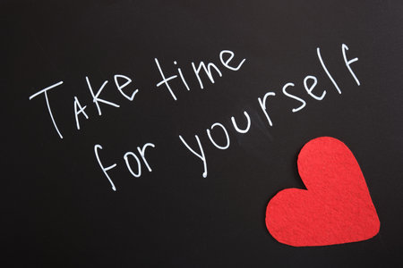 inscription take time for yourself and felt heart, text with white chalk marker on black board,...