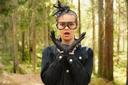 portrait of teenage girl in Halloween outfit in forest or park, kid making faces and gesturing, copy spaceの写真素材