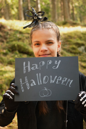 teenage girl holding sign happy halloween outsideの写真素材