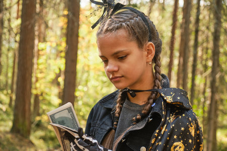 dark skinned teenage girl dressed as witch or wizard counts and plays with money, trick or treat concept, halloween earningsの写真素材