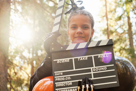 portrait of teenage girl in Halloween costume with movie clapperboard outsideの写真素材
