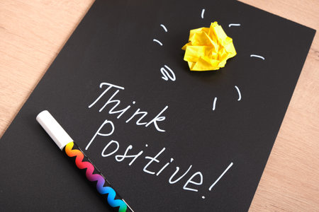 chalk marker writing on black daughter, stay positive, motivational slogan, yellow crumpled paper as light bulb, idea concept, creative artの写真素材