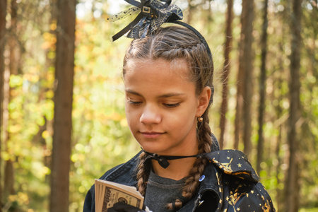dark skinned teenage girl dressed as witch or wizard playing with money, trick or treat concept,...