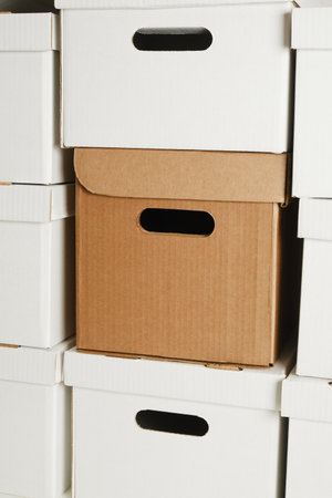 one brown box and a pile of white cardboard boxes with slots for holding, storage boxes, wall of boxesの写真素材