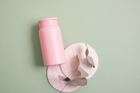 reusable skin care pads and cosmetic bottle mockup on green background, pastel shadesの写真素材