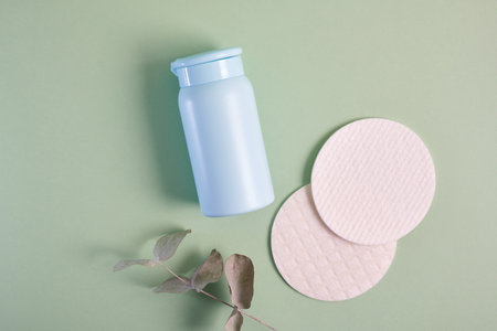 reusable skin care pads and cosmetic bottle mockup on green background, pastel shadesの写真素材