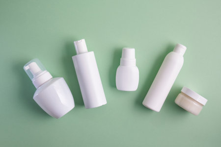 various white bottles of different types on pastel green background top viewの写真素材