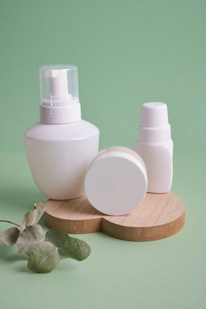 various white bottles on pastel green background, cosmetic containers stand on heart-shaped tray, natural products and self-careの写真素材