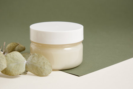 mock up natural cosmetics eucalyptus based product, transparent jar of cream or ointment and eucalyptus branch on green backgroundの写真素材