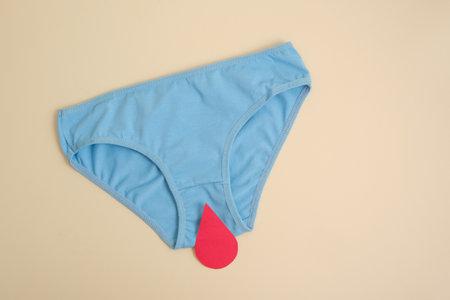 menstruation concept, women's health care and paper blood drops and women's panties on a beige...