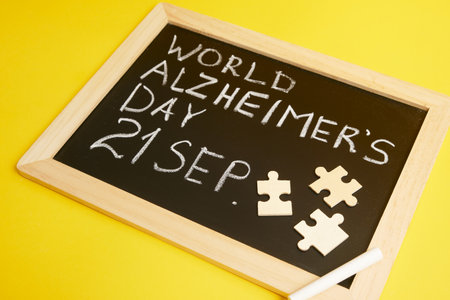 chalk inscription September 21 world Alzheimer's day and puzzles, concept of cognitive decline of the brain yellow backgroundの写真素材