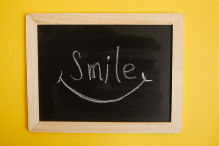 drawn smile and inscription on black chalk board, yellow backgroundの写真素材
