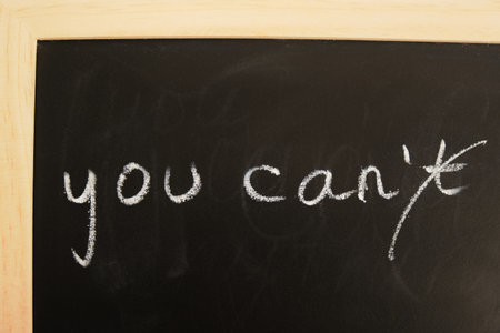 chalk inscription on daughter "you can" with crossed out letter n, chalk board on blue backgroundの写真素材