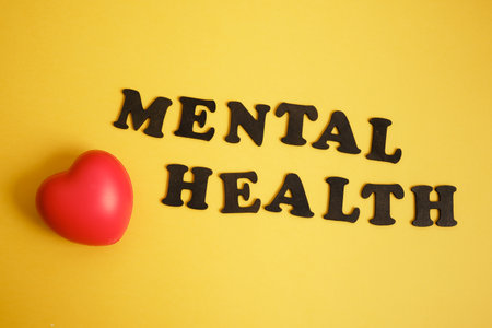 red heart and inscription mental health on yellow background, psychological health conceptの写真素材