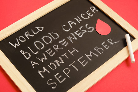 blood cancer concept, blood cancer awareness month, chalk writing on black board, red backgroundの写真素材