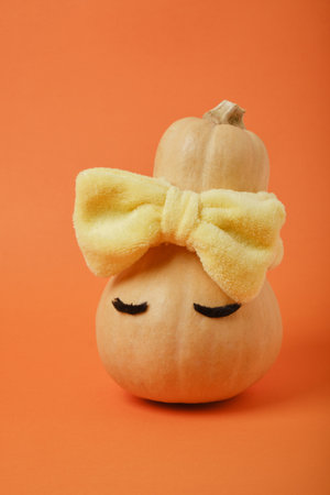 Autumn pumpkin with eyes in a bandage on an orange background, copy space, mock upの写真素材
