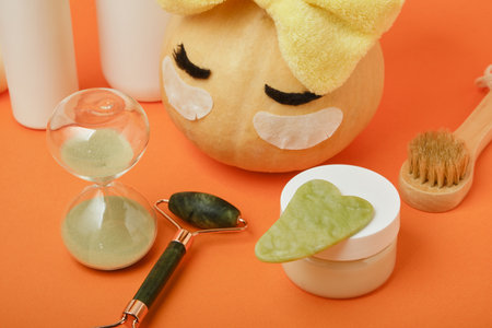 Seasonal skin care concept, pumpkin and cosmetics on orange background, mock up, skin massage and moisturizing, self-care, hourglassの写真素材
