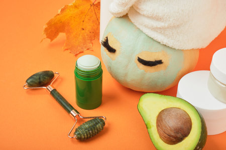Avocado mask stick concept, pumpkin and avocado on an orange background, autumn beauty careの写真素材