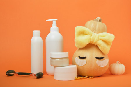 Seasonal skin care concept, pumpkin and cosmetics on orange background, mock up, skin massage and moisturizing, self-careの写真素材