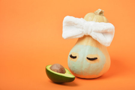 Pumpkin and avocado on an orange background, beauty treatments for autumn skin care, copy space, mock upの写真素材