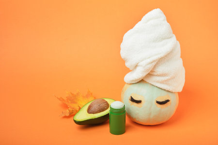 Avocado mask stick concept, pumpkin and avocado on an orange background, autumn beauty careの写真素材