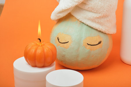Mock-up jars of cream and yellow pumpkin in a clay mask and a towel on the head Natural organic spa cosmetics concept. Vitamin intense seed of pumpkin cream concept.の写真素材