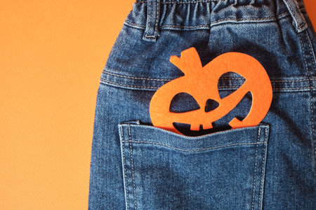 Blue jeans and a felt pumpkin on an orange backgroundの写真素材
