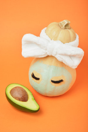 Pumpkin and avocado on an orange background, beauty treatments for autumn skin care, copy space, mock upの写真素材
