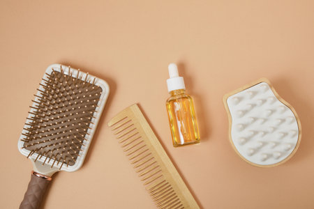 Comb, serum, hair brush and scalp massager on beige background