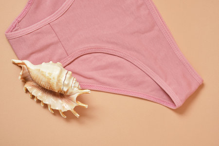 Women's cotton panties and a large seashell on a beige background, women's health conceptの写真素材