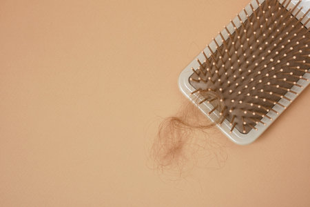 Massage comb with a strand of hair, beige background, hair loss problem, scalp healthの写真素材