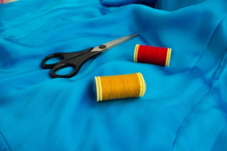 Sewing thread and scissors on blue silk