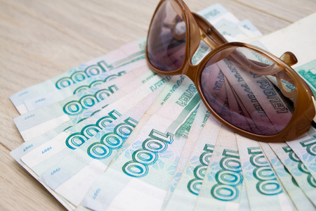business, finance, saving, banking, travel and people concept - close up bundle of money Russian Banknotes thousand rubles with sun glassesの写真素材