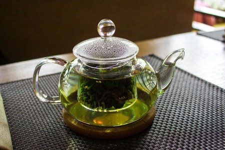 Beverages, good morning and breakfast concept - Cup of white green tea and teapot on the tableの写真素材